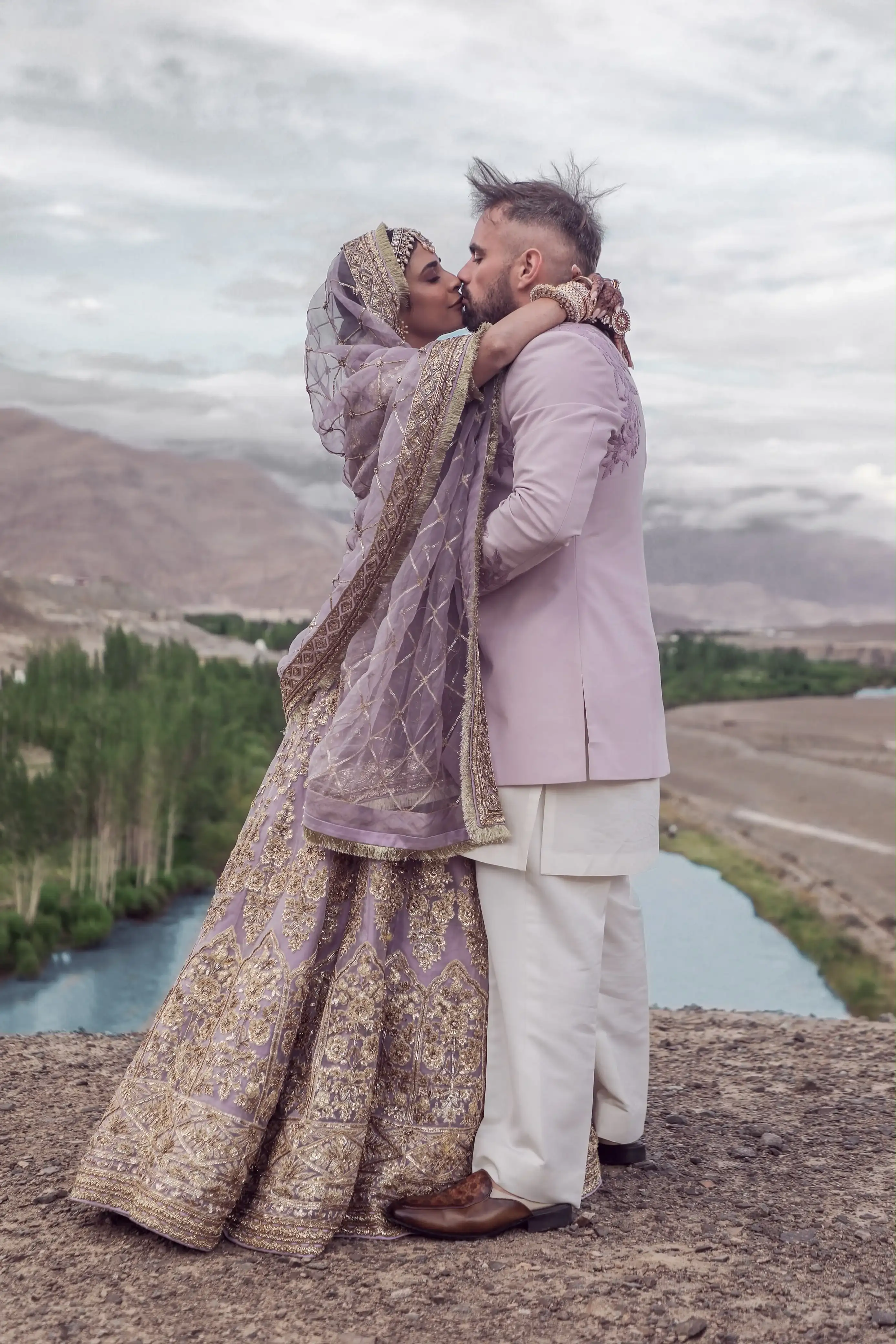 Bride and groom kissing on a cliff above the Indus valley, Ladakh
